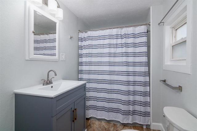 bathroom featuring a shower with shower curtain, vanity, toilet, and a textured ceiling