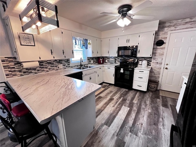 kitchen with black appliances, white cabinets, sink, ceiling fan, and kitchen peninsula