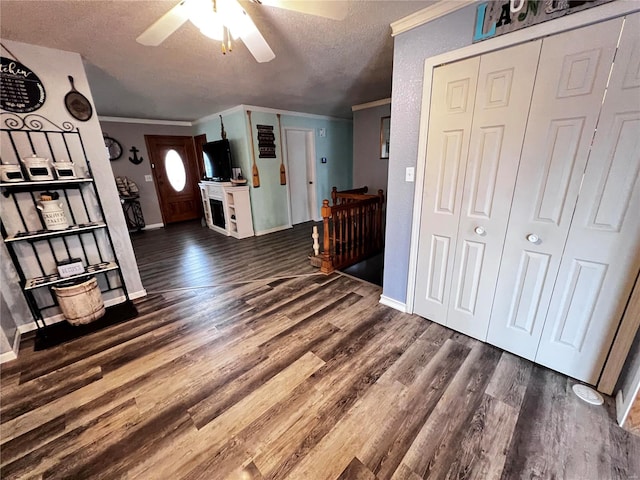 entryway featuring a textured ceiling, dark hardwood / wood-style floors, ceiling fan, and ornamental molding