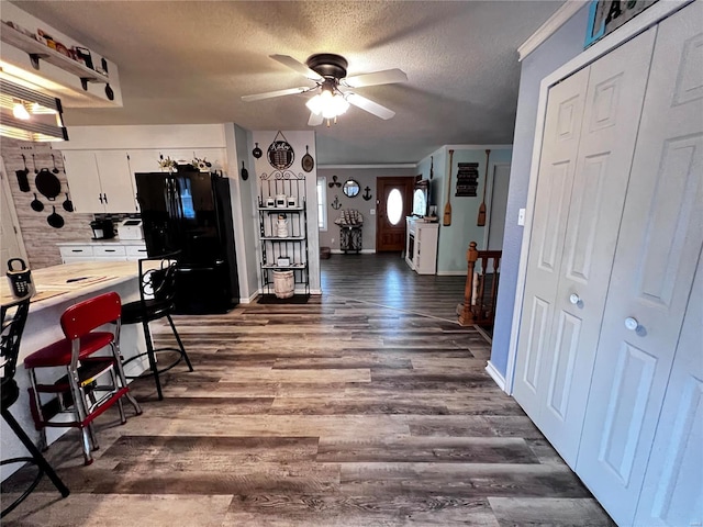 kitchen featuring white cabinetry, ceiling fan, dark wood-type flooring, black fridge, and a textured ceiling