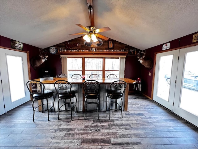 dining room featuring plenty of natural light, lofted ceiling, and a textured ceiling