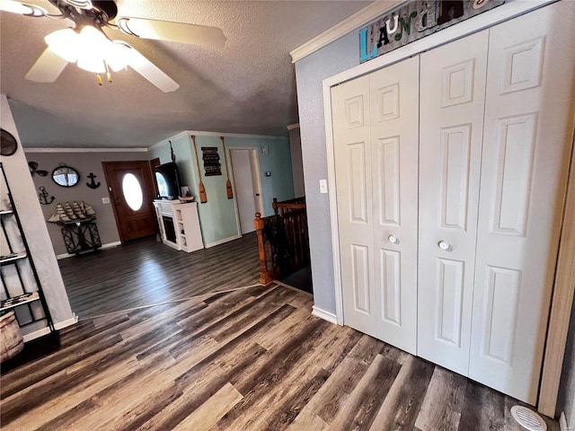 entryway with a textured ceiling, ceiling fan, dark hardwood / wood-style flooring, and crown molding