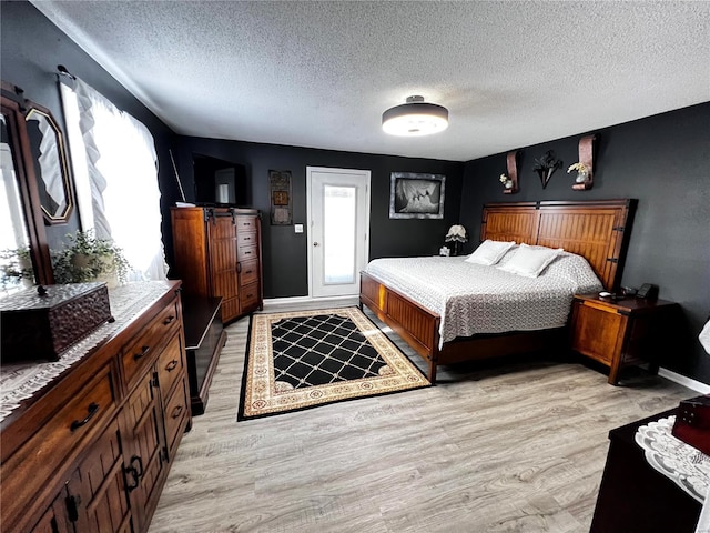 bedroom with a textured ceiling, light hardwood / wood-style flooring, and multiple windows