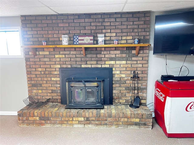 room details with a wood stove and a drop ceiling