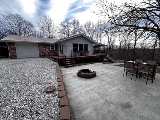 view of patio featuring a wooden deck, a garage, and an outdoor fire pit