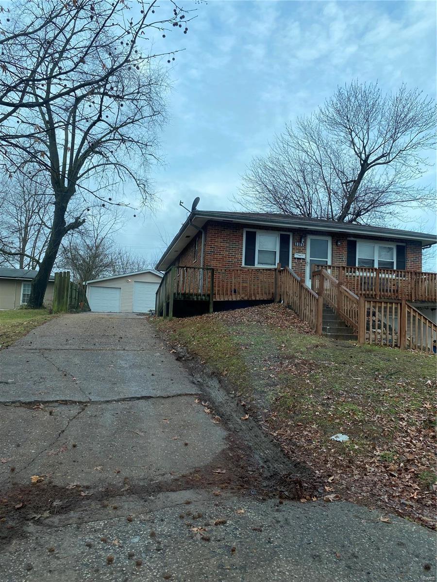 view of front of house featuring a garage, a deck, and an outbuilding