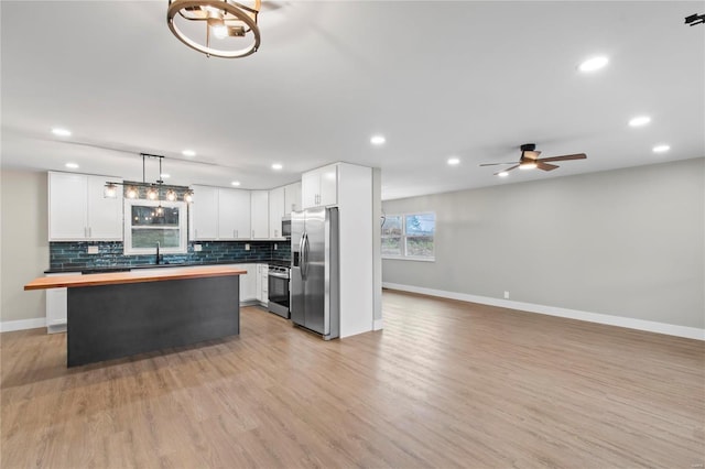 kitchen with sink, white cabinets, stainless steel appliances, and decorative light fixtures