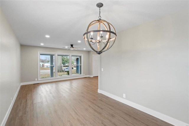 interior space featuring ceiling fan with notable chandelier and hardwood / wood-style flooring