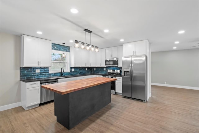 kitchen with white cabinets, appliances with stainless steel finishes, a center island, and hanging light fixtures