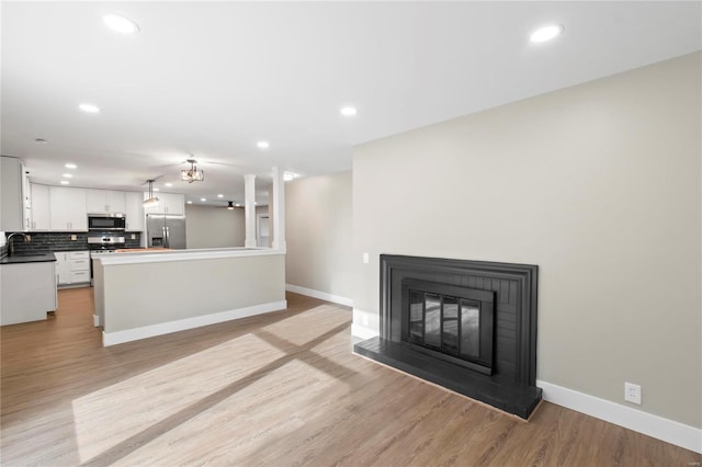 unfurnished living room with sink and light hardwood / wood-style flooring