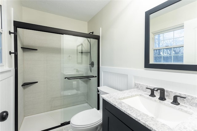 bathroom featuring a textured ceiling, vanity, an enclosed shower, and toilet