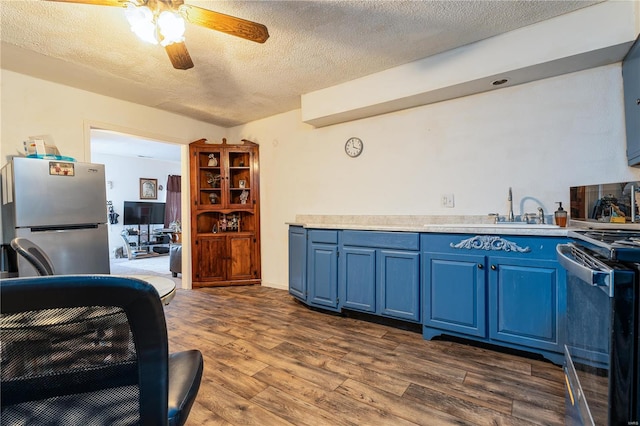 kitchen featuring blue cabinets, sink, dark hardwood / wood-style flooring, stainless steel appliances, and a textured ceiling