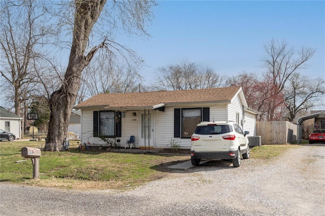 view of front of home with a front yard, central air condition unit, fence, and a shingled roof