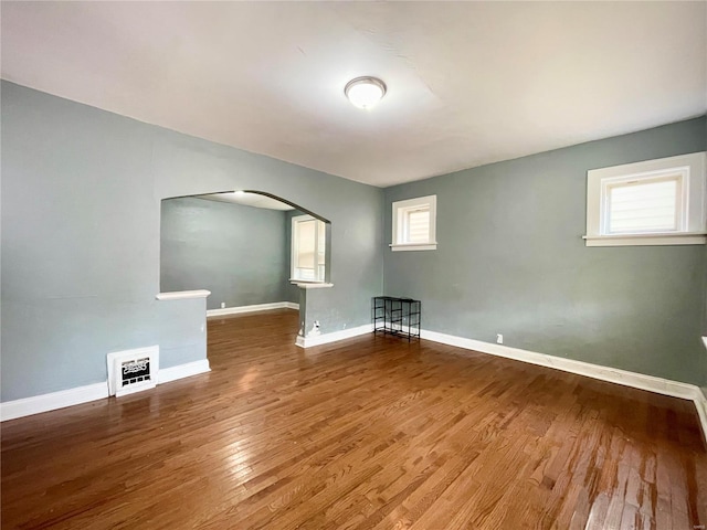 empty room with a wealth of natural light and hardwood / wood-style floors