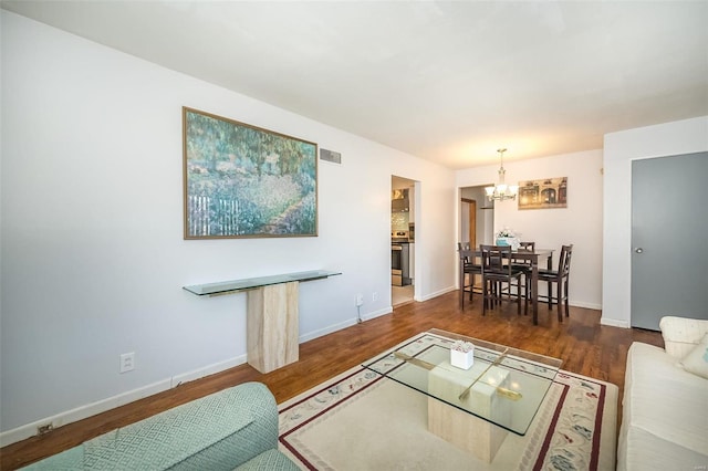 living room featuring a chandelier and dark wood-type flooring