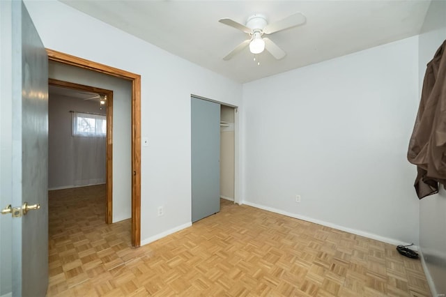 unfurnished bedroom featuring ceiling fan, a closet, and light parquet floors