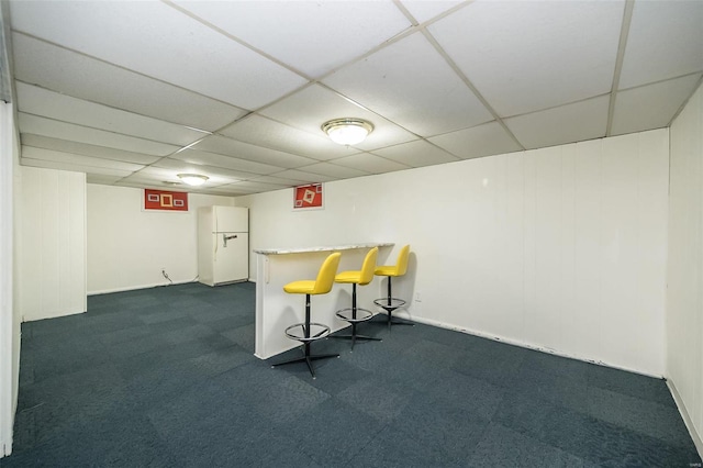 bar with a paneled ceiling, dark carpet, and white refrigerator