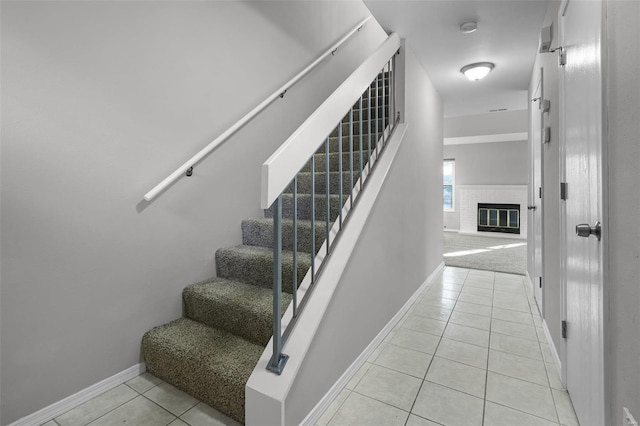 stairway featuring tile patterned floors and a brick fireplace