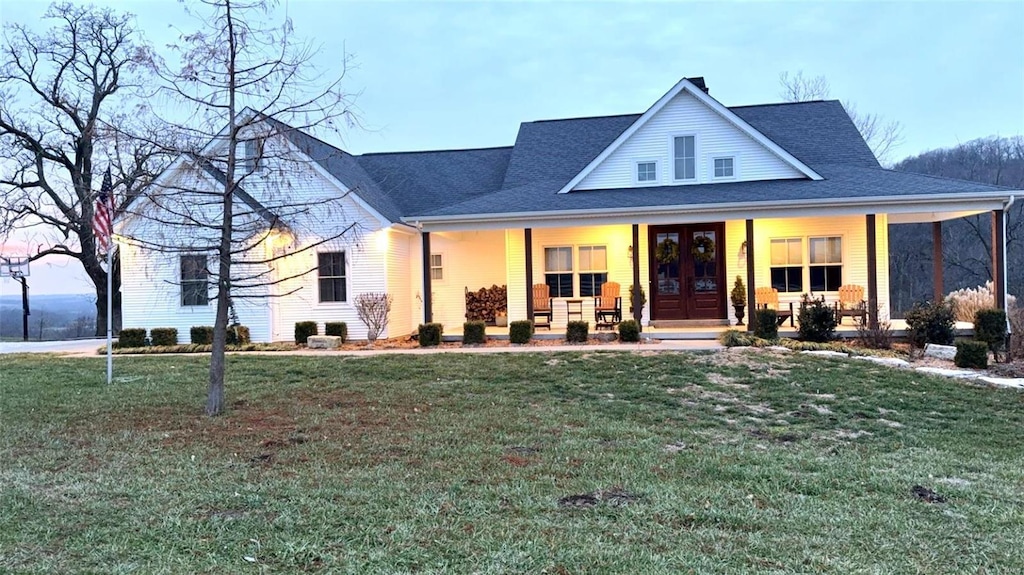 view of front of house featuring a front yard, a porch, and french doors