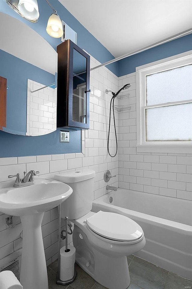 bathroom with decorative backsplash, tile walls, tile patterned flooring, toilet, and tiled shower / bath