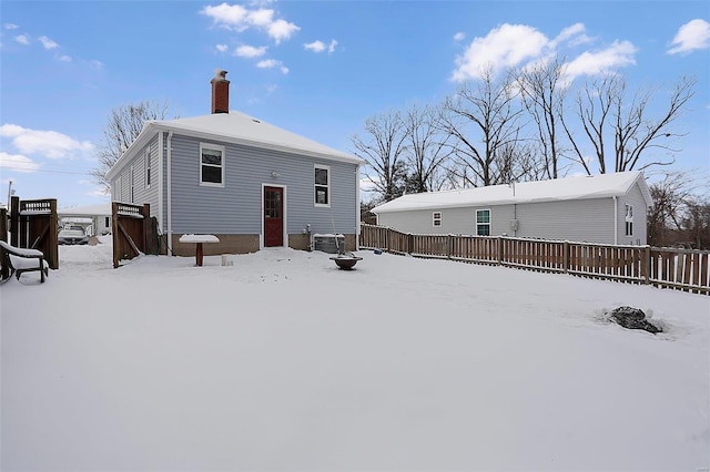 snow covered rear of property featuring central AC unit