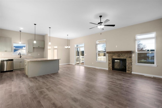 kitchen featuring a center island, sink, hanging light fixtures, stainless steel dishwasher, and a fireplace