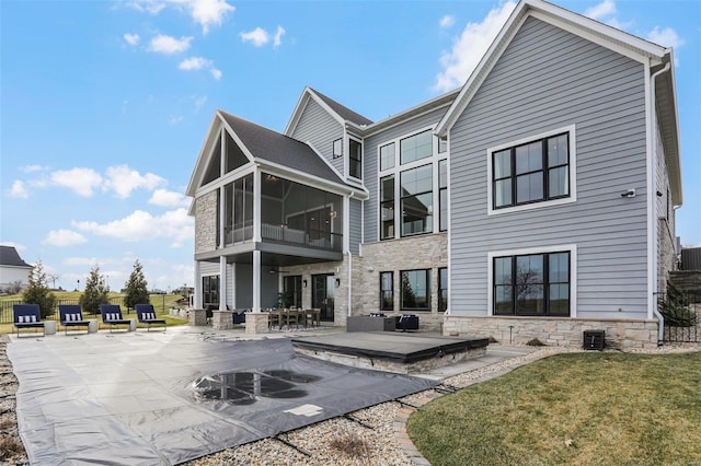 rear view of property featuring a patio area, a sunroom, a yard, and central AC