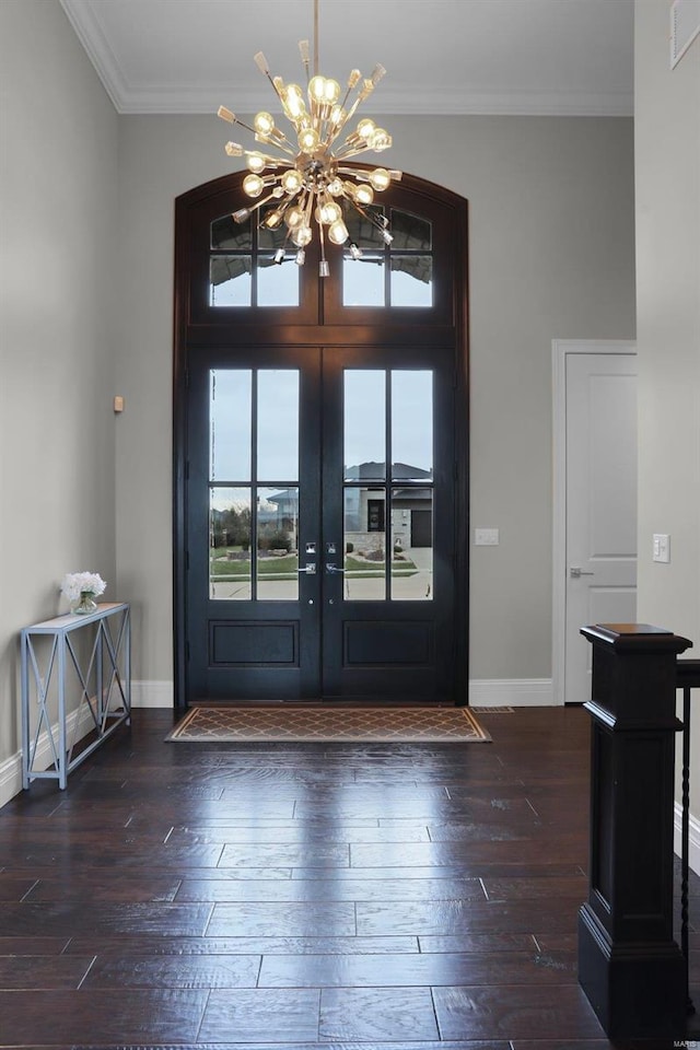 entrance foyer featuring french doors, dark hardwood / wood-style flooring, crown molding, and a notable chandelier