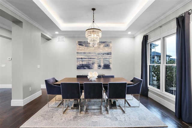 dining area with ornamental molding, dark hardwood / wood-style flooring, a tray ceiling, and a notable chandelier