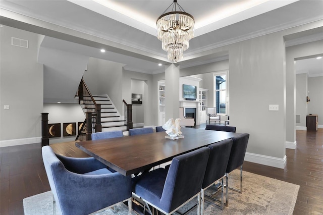 dining space with built in shelves, dark hardwood / wood-style flooring, ornamental molding, and an inviting chandelier