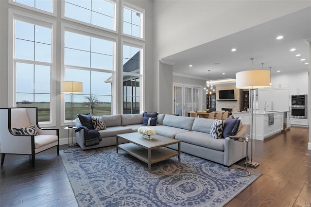 living room featuring a towering ceiling, crown molding, sink, an inviting chandelier, and dark hardwood / wood-style floors