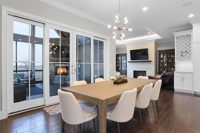 dining area with a fireplace, dark hardwood / wood-style floors, a raised ceiling, and crown molding