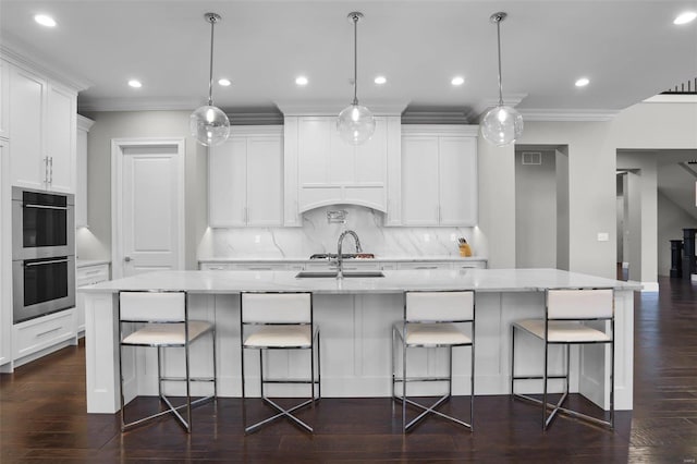 kitchen with a breakfast bar area, pendant lighting, stainless steel double oven, and a spacious island