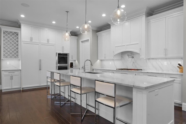 kitchen with stainless steel appliances, a spacious island, sink, white cabinets, and hanging light fixtures