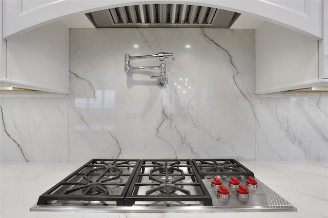 kitchen featuring white cabinets, decorative backsplash, and stainless steel gas stovetop