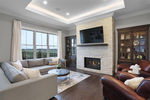 living room with a raised ceiling, crown molding, a fireplace, and dark wood-type flooring