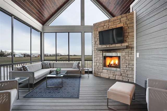 sunroom featuring vaulted ceiling, a stone fireplace, and wood ceiling