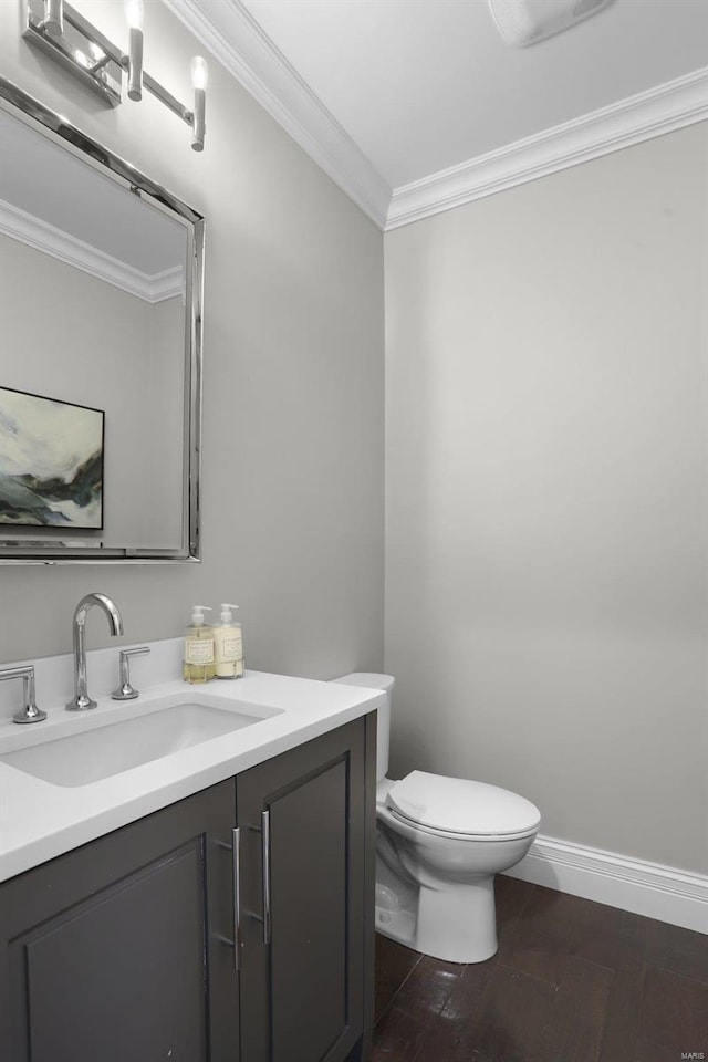 bathroom with vanity, toilet, wood-type flooring, and crown molding