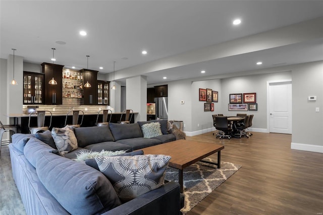 living room featuring bar area and dark wood-type flooring