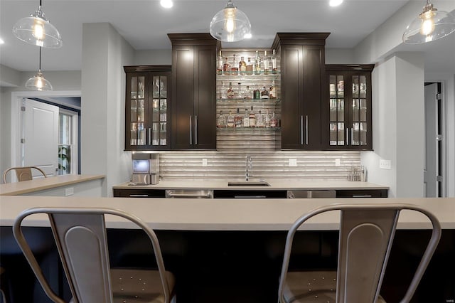 bar with dark brown cabinetry, tasteful backsplash, and sink