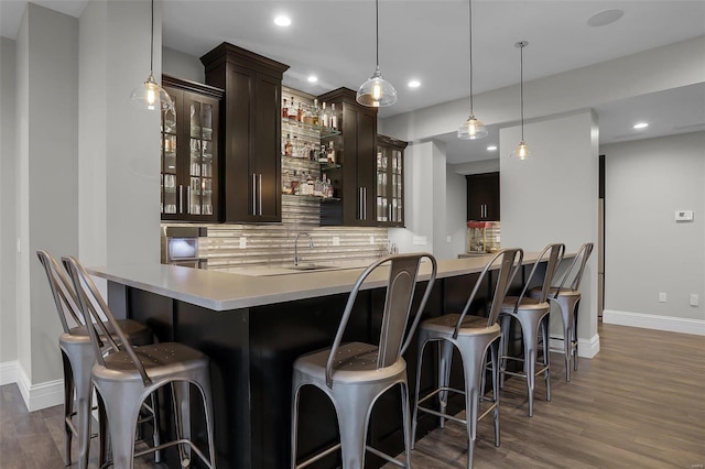 bar with sink, decorative backsplash, decorative light fixtures, dark hardwood / wood-style flooring, and dark brown cabinetry