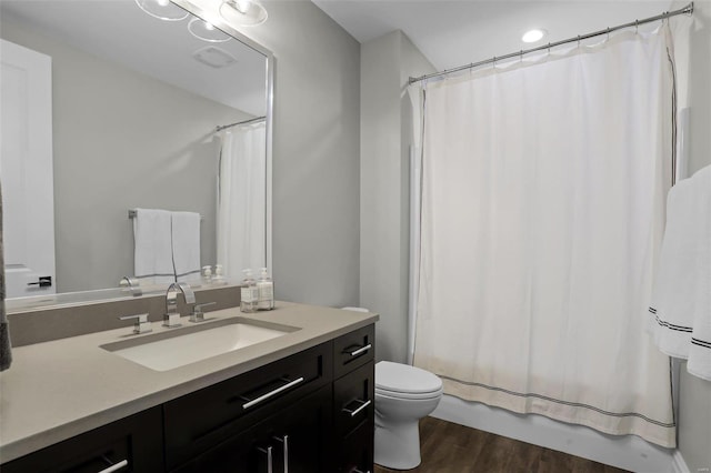 full bathroom with hardwood / wood-style floors, vanity, shower / tub combo, and toilet