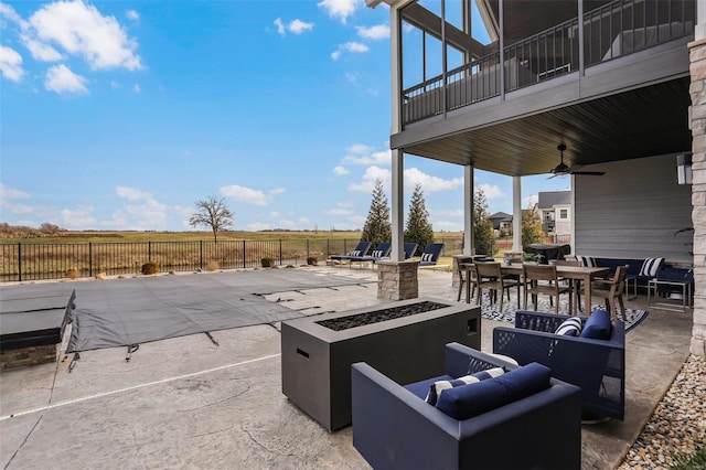 view of patio featuring ceiling fan, a rural view, a balcony, and an outdoor living space with a fire pit