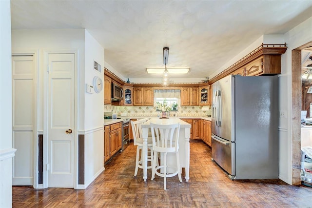 kitchen with stainless steel appliances, dark parquet floors, decorative backsplash, a kitchen island, and pendant lighting