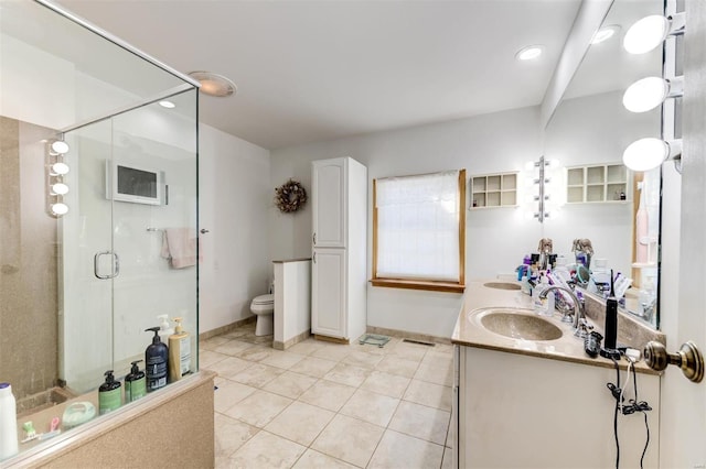 bathroom with toilet, vanity, a shower with shower door, and tile patterned floors