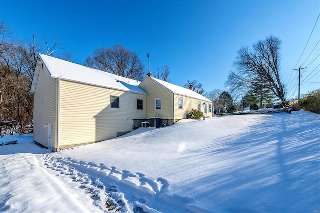 snow covered property with central AC