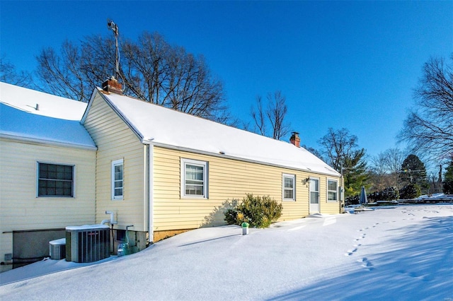 snow covered rear of property with central AC unit