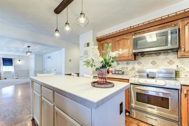 kitchen with stainless steel appliances, decorative light fixtures, a center island, and decorative backsplash