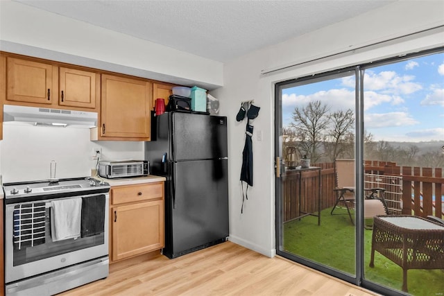 kitchen featuring black refrigerator, stainless steel range oven, a textured ceiling, and light hardwood / wood-style flooring