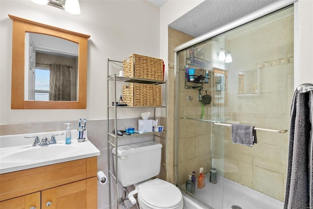 bathroom with vanity, a shower with shower door, a textured ceiling, and toilet